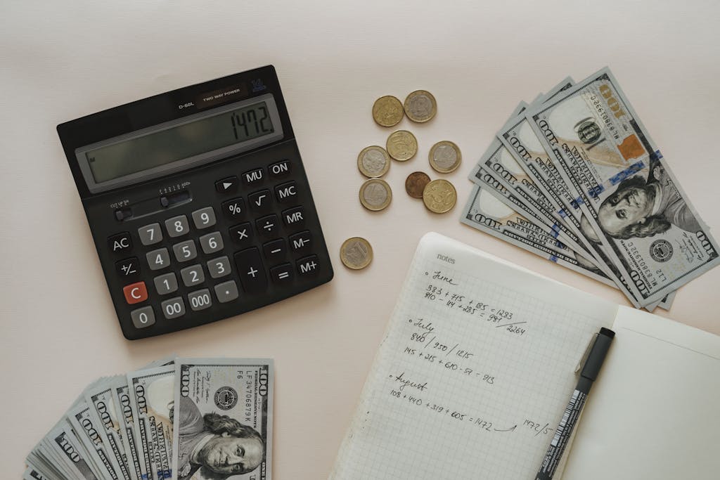 Flat lay of calculator, cash, coins, and handwritten notes for budget planning.